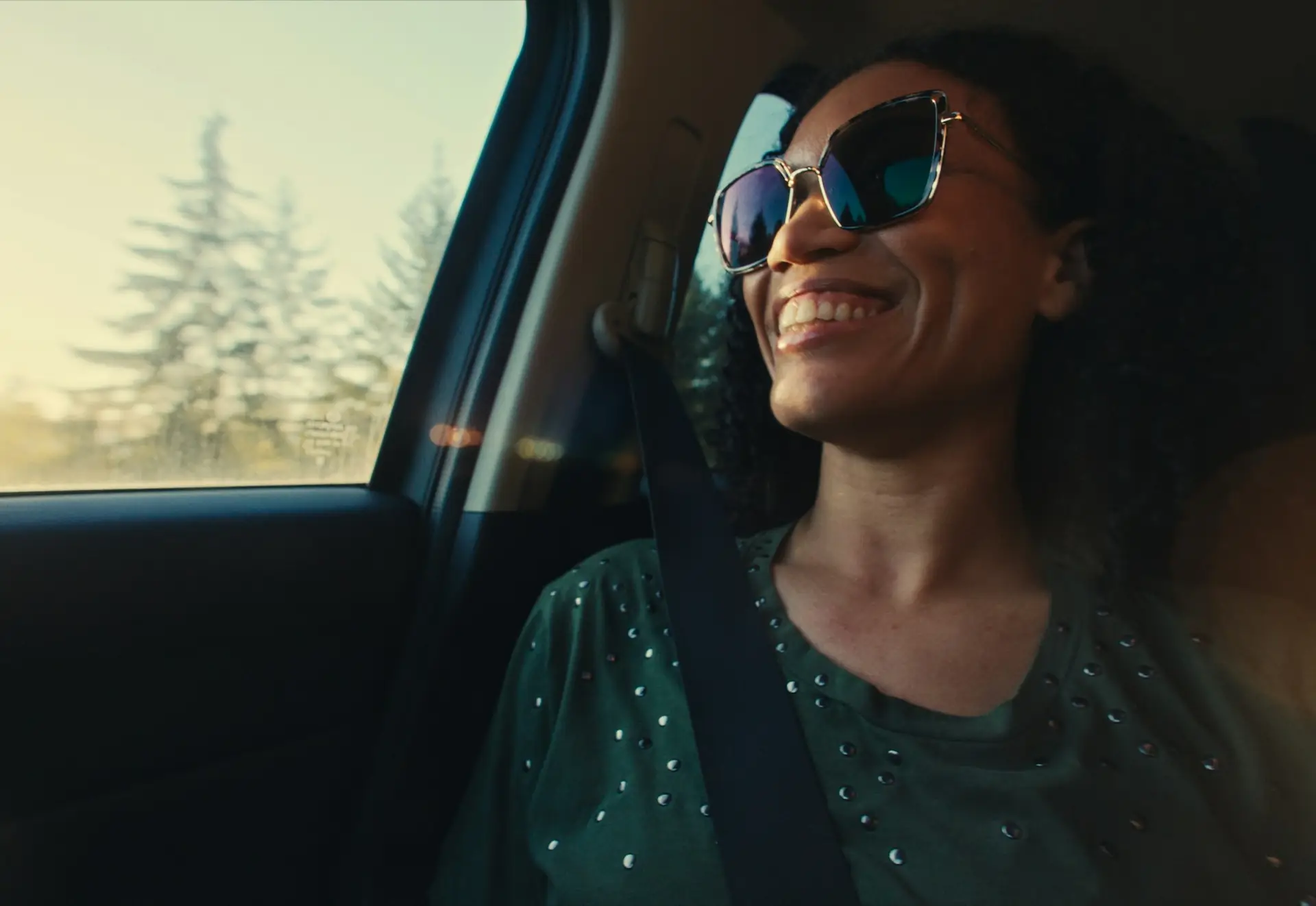 A smiling woman in sunglasses at the wheel
