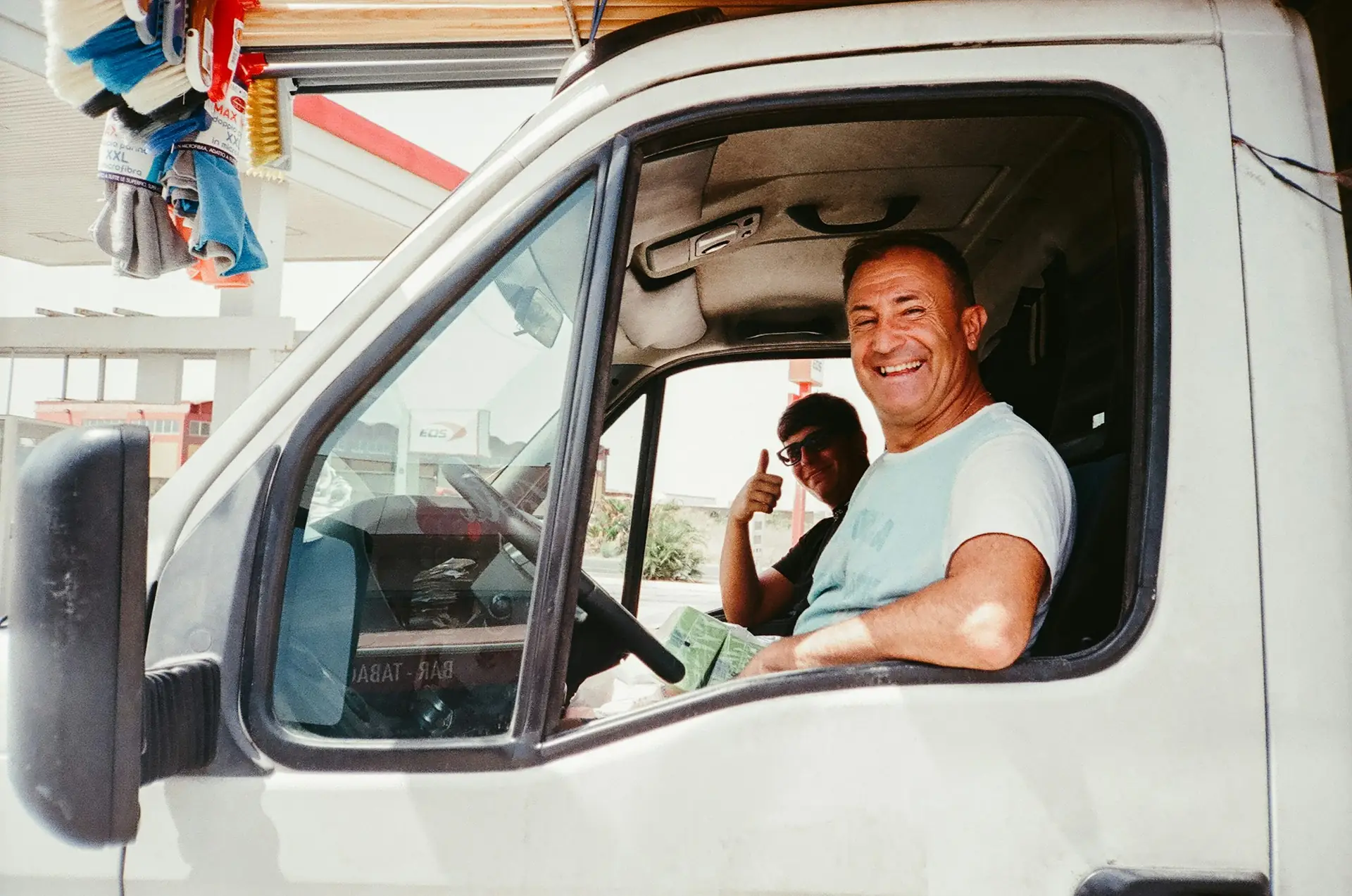 Two smiling men in the cab of a van