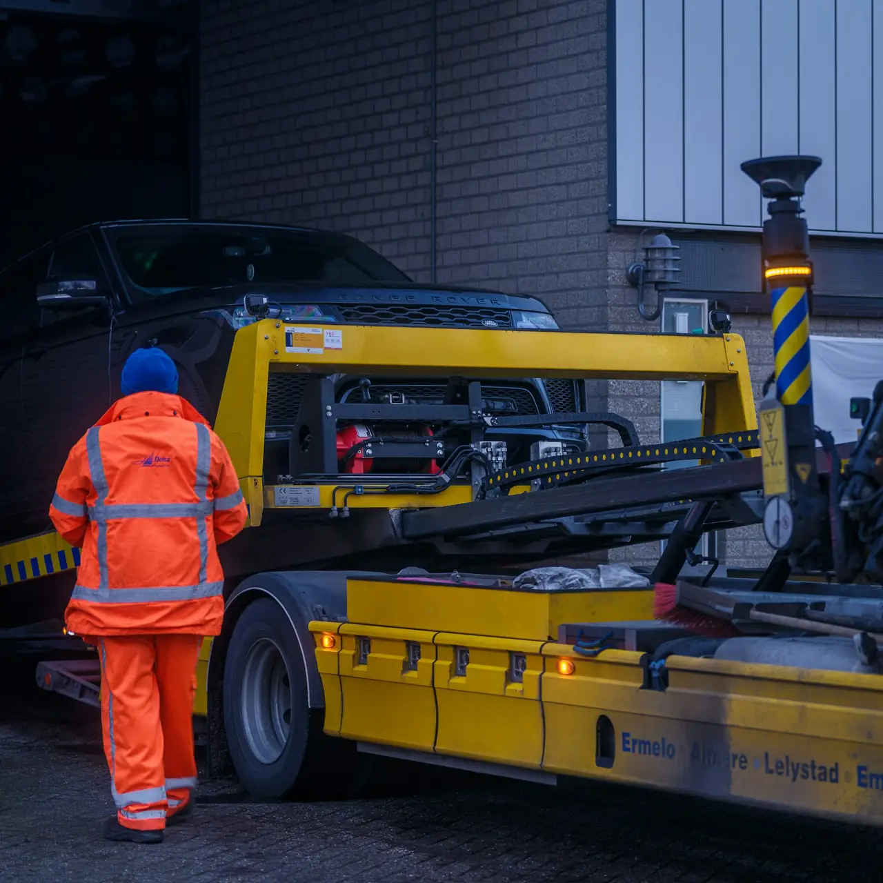 A tow operator loading an SUV onto a flatbed